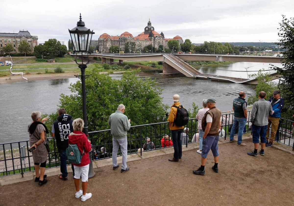 Viandantes observan el puente Carola parcialmente derrumbado sobre el río Elba, en el centro de la ciudad de Dresde.