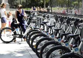 Una mujer coge una bicicleta eléctrica de una estación para compartir bicicletas, en Madrid.