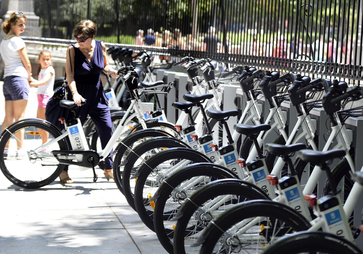 Una mujer coge una bicicleta eléctrica de una estación para compartir bicicletas, en Madrid.