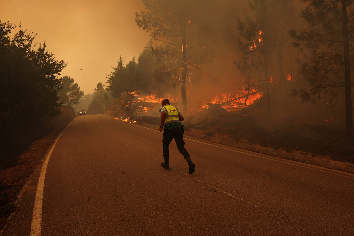 Un policía corre por una carretera rodeada por el fuego en Sao Pedro do Sul (Portugal).