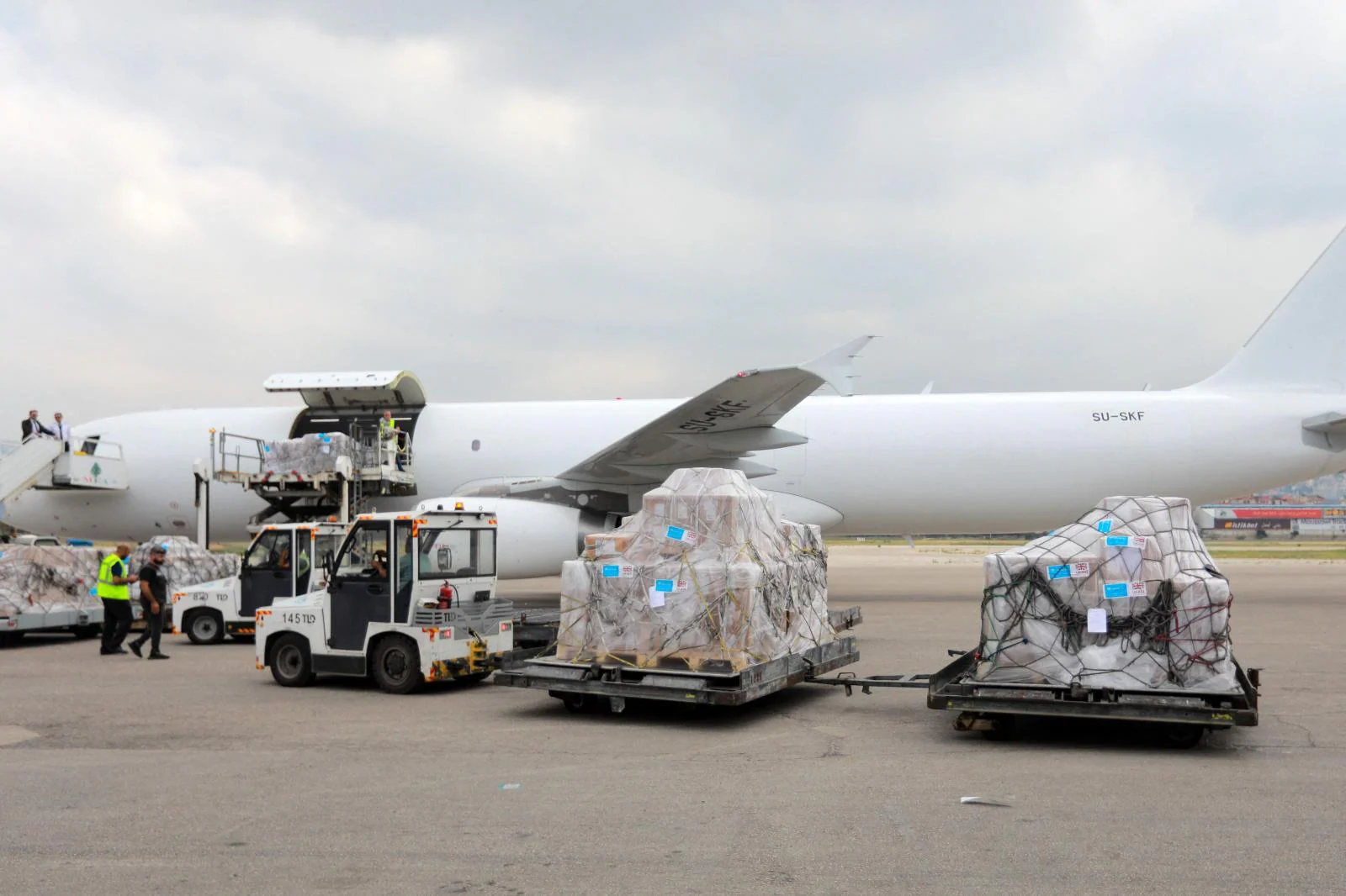 Unicef descarga ayuda humanitario en el aeropuerto de Beirut mientras, abajo, dos civiles huyen de la devastación.