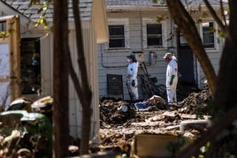 Dos voluntarios inspeccionan una vivienda destruida.