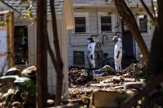 Dos voluntarios inspeccionan una vivienda destruida.