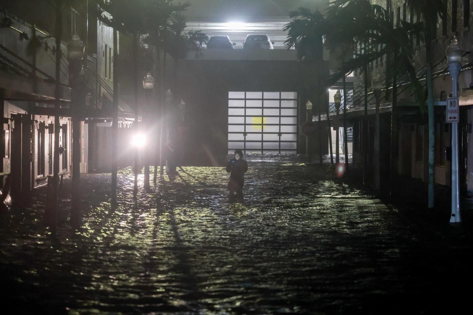 La gente toma fotografías y vídeos mientras camina por las calles inundadas por las inundaciones después de que el huracán Milton tocara tierra en Fort Myers, Florida, el 9 de octubre de 2024.