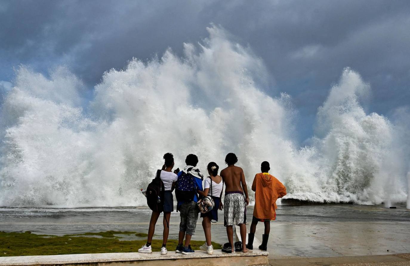 Jóvenes observan las olas rompiendo en el malecón de La Habana por el paso del huracán Milton.