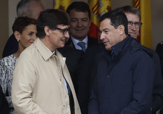 Salvador Illa conversa antes del desfile con el presidente andaluz, Juanma Moreno.