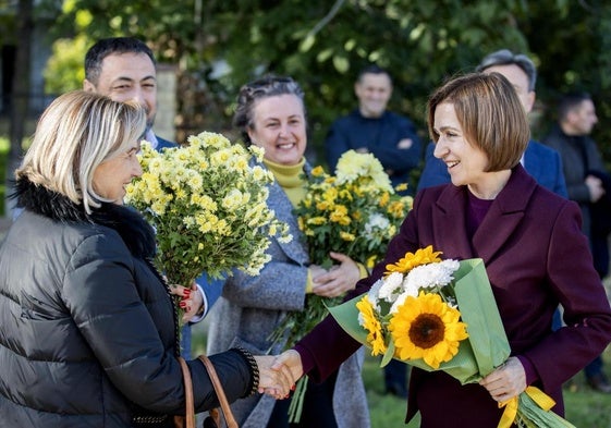 Una simpatizante estrecha la mano a la actual presidenta moldava, Maia Sandu, favorita en las encuestas.