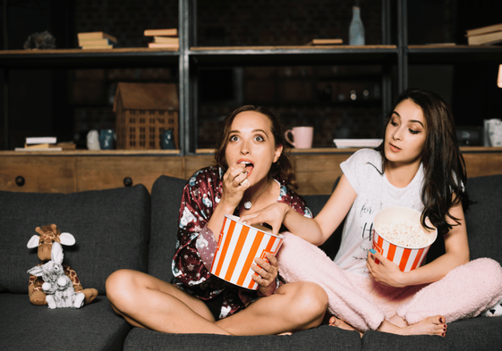 2 chicas comen palomitas juntas recién hechas.