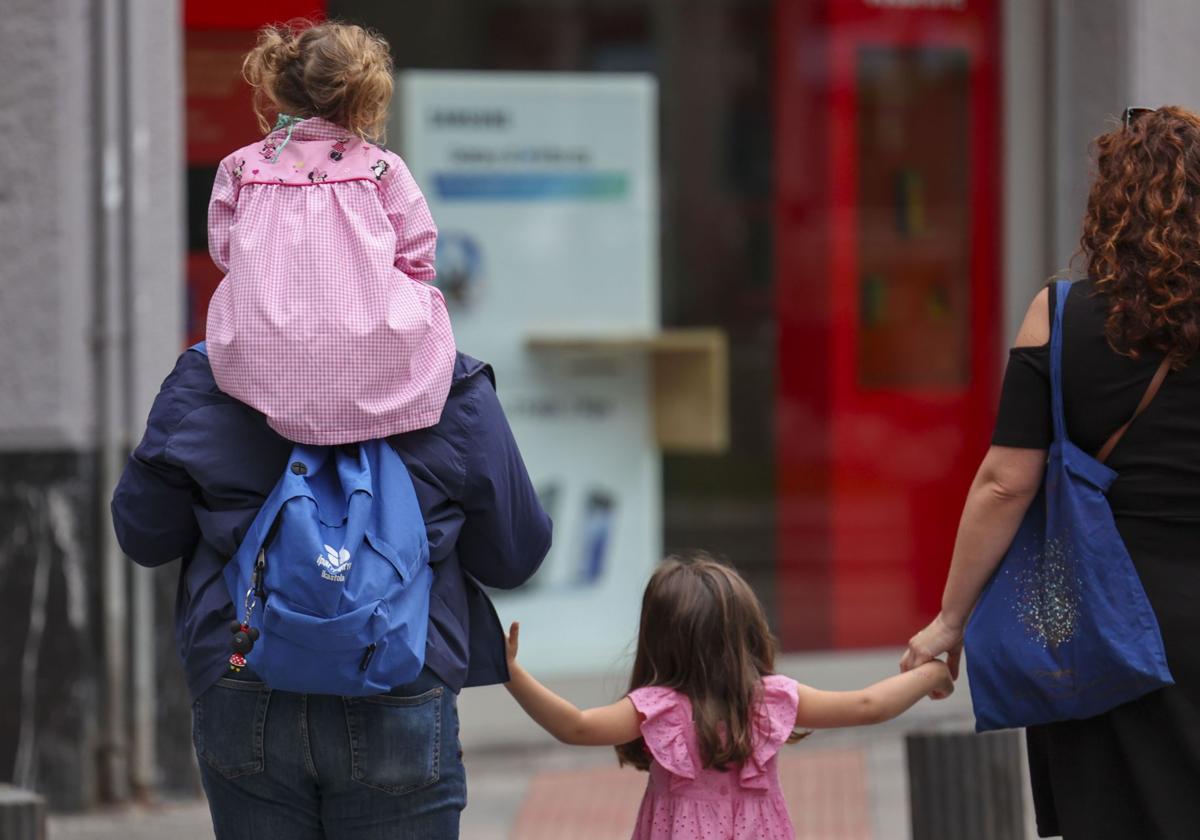 Unos padres acompañan a sus hijas al colegio.