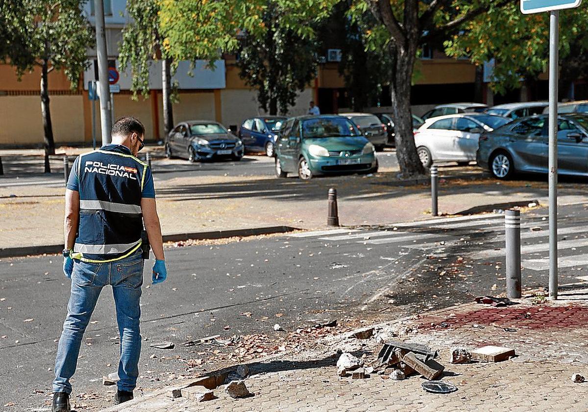 Un agente inspecciona el lugar del tiroteo registrado en el Polígono Sur de Sevilla.