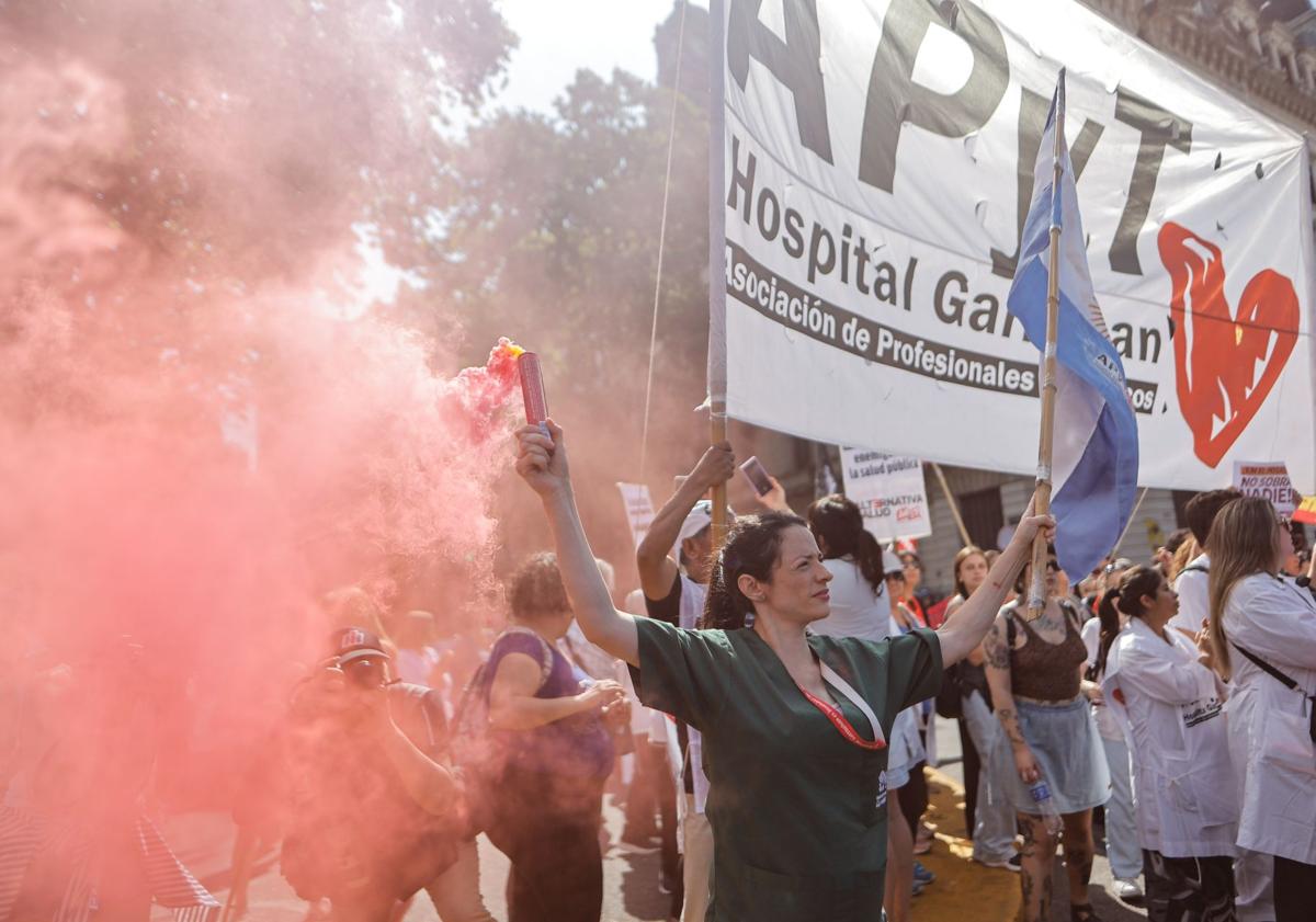 Imagen principal - Trabajadores del sector de la salud, en las dos primeras imágenes, y de la educación, en la última, protestan contra los recortes de Milei en los sectores.