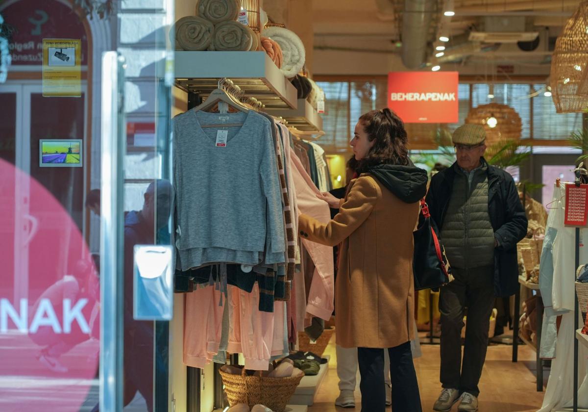 Una persona mirando ropa en una tienda.