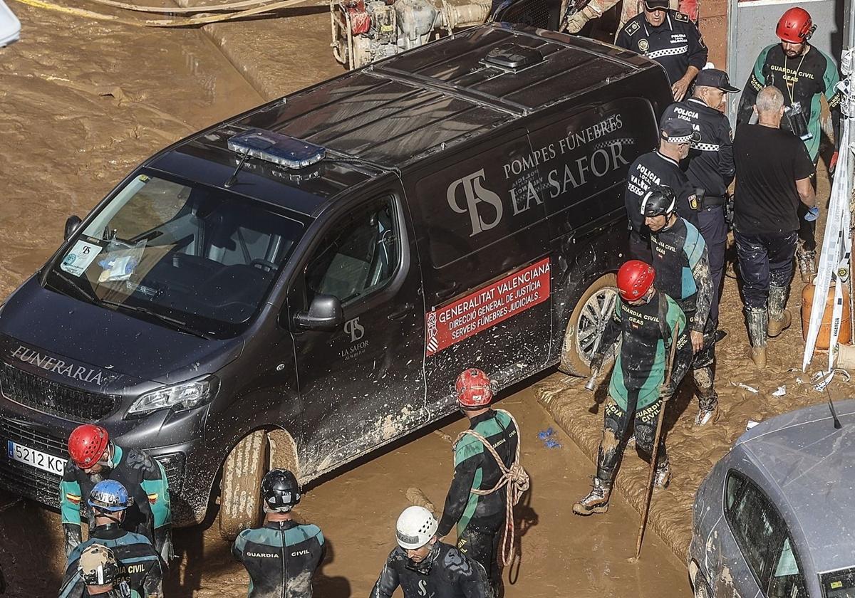 Un furgón de la funeraria sale de un garaje con cadáveres localizados tras el paso de la DANA en el barrio de la Torre, en Valencia.