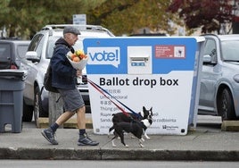 Un hombre pasea por una calle de Seattle en la que se ubica una urna electoral.