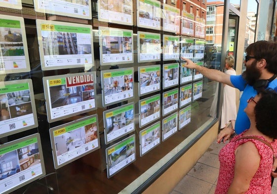 Una pareja mirando un escaparate de una inmobiliaria.