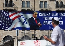 Un hombre camina junto a un cartel instalado en Jerusalén para felicitar la victoria de Donald Trump en las presidenciales de Estados Unidos.