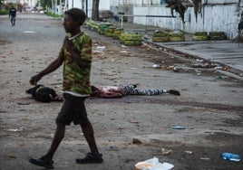 Un hombre pasa frente unos cadáveres en una calle de Puerto Príncipe.