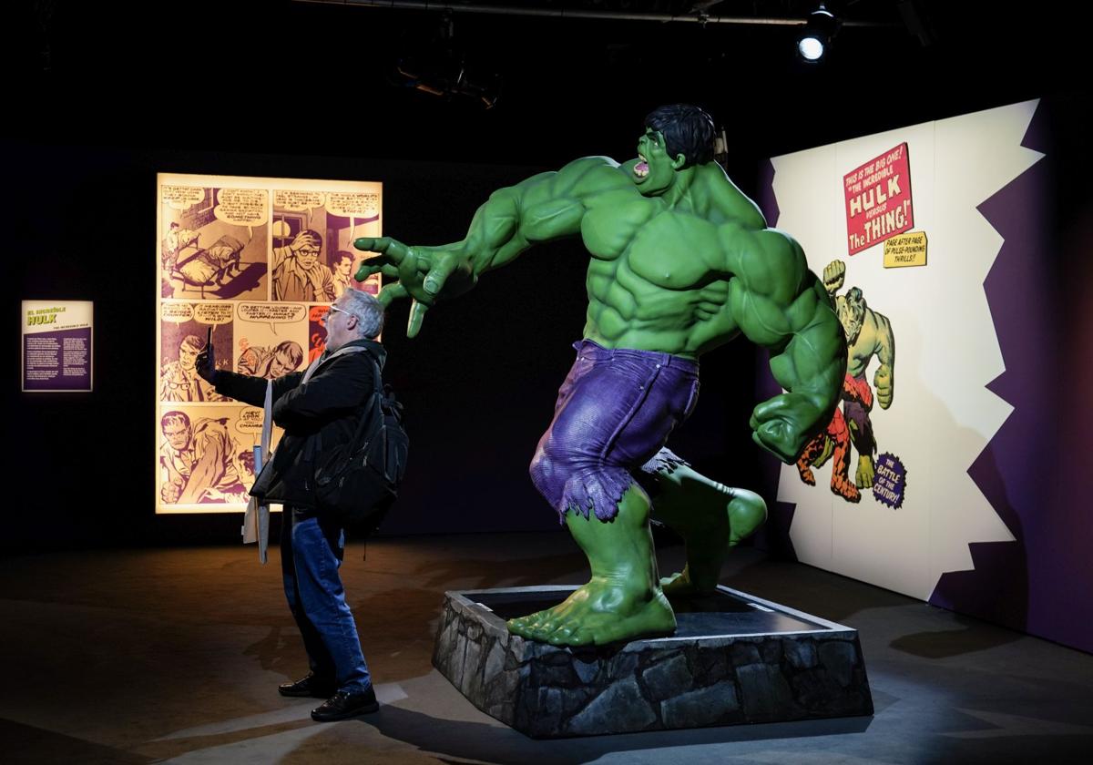 Un visitante se hace un selfi junto a una figura a tamaño real del Increíble Hulk.