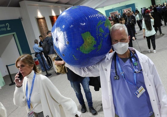 Joe Vipond, miembro de la Asociación de Médicos por el Medio Ambiente, trasporta un globo terráqueo 'enfermo' en la Cumbre de Bakú.