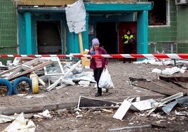 Una mujer lleva sus pertenencias personales fuera de un edificio residencial dañado por un ataque con misiles rusos en Sumi.