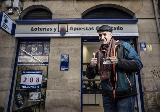 Amadeo Marín, con un décimo de la Lotería de Navidad, delante de una Administración de Logroño.