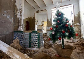 Un árbol de Navidad decora una planta baja repleta de escombro y lodo en una cas de Paiporta (Valencia).