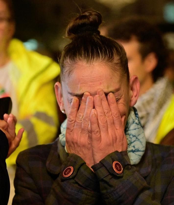 Imagen secundaria 2 - En la imagen superior, varios manifestantes lanzan barro antes las puertas de un edificio oficial, debajo una pancarta criticando la tardanza en los avisos de la Generalitat por la DANA y, por última, una mujer no puede resistir emocionarse durante la protesta.