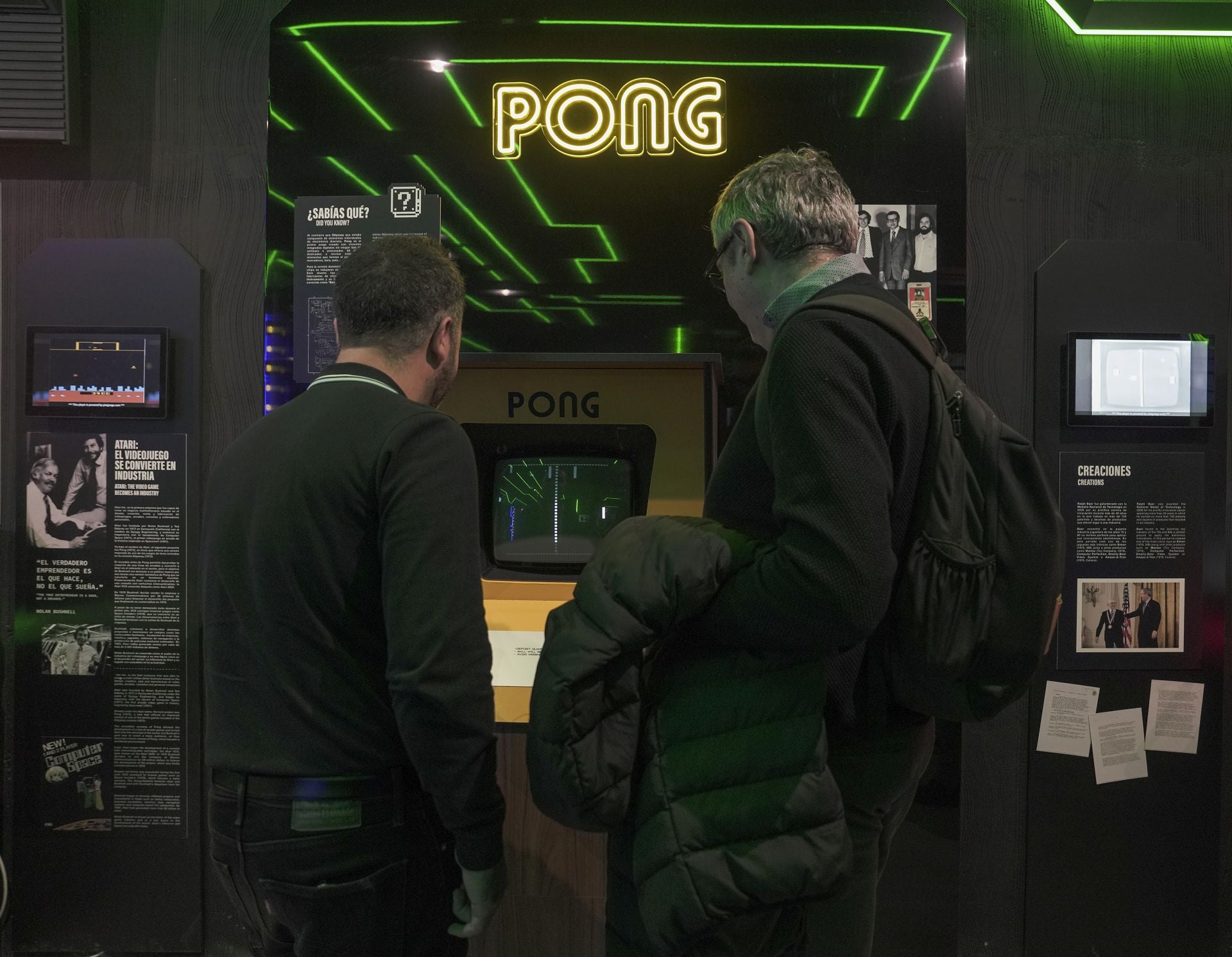 Dos personas miran la pantalla del juego 'Pong'