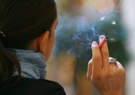 Una mujer fuma un cigarrillo.