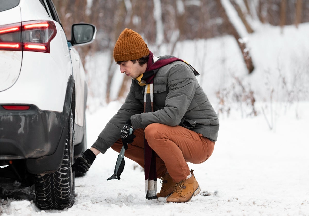 Hombre mirando sus ruedas en las que tiene que poner cadenas para la nieve