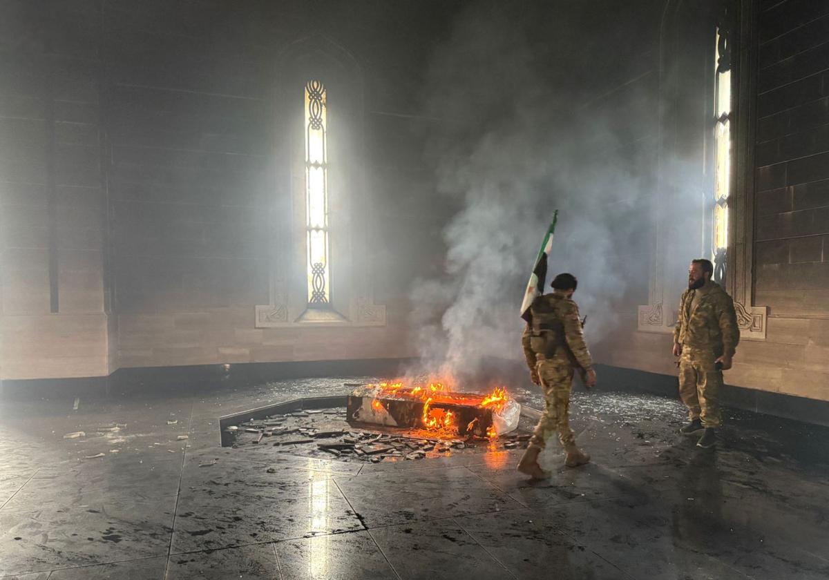 Combatientes rebeldes junto a la tumba en llamas del difunto presidente de Siria, Hafez al Assad.