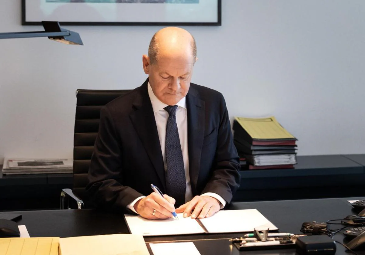 Olaf Scholz firma la petición de moción de censura en su despacho.