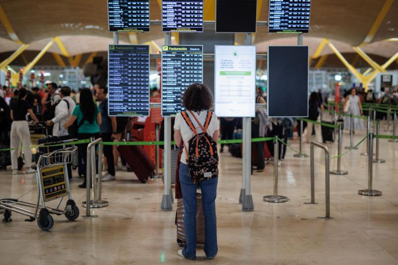 Pasajera frente a las pantallas en el Aeropuerto de Adolfo Suárez-Madrid Barajas.