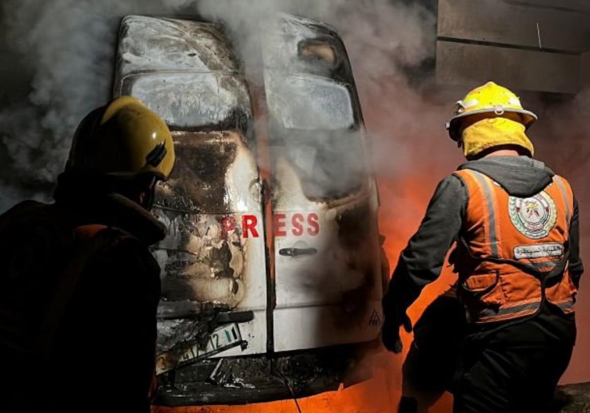 Miembros de Defensa Civil apagan la furgoneta incendiada en la que estaban los cinco periodistas del canal de televisión Al-Quds Al-Youm.