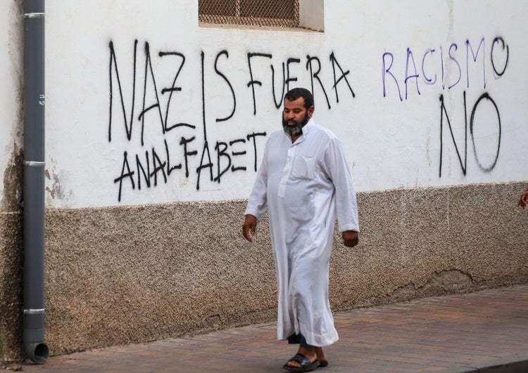 Un vecino con vestimenta árabe pasea por Torre Pacheco entre pintadas de rechazo hacia el racismo.