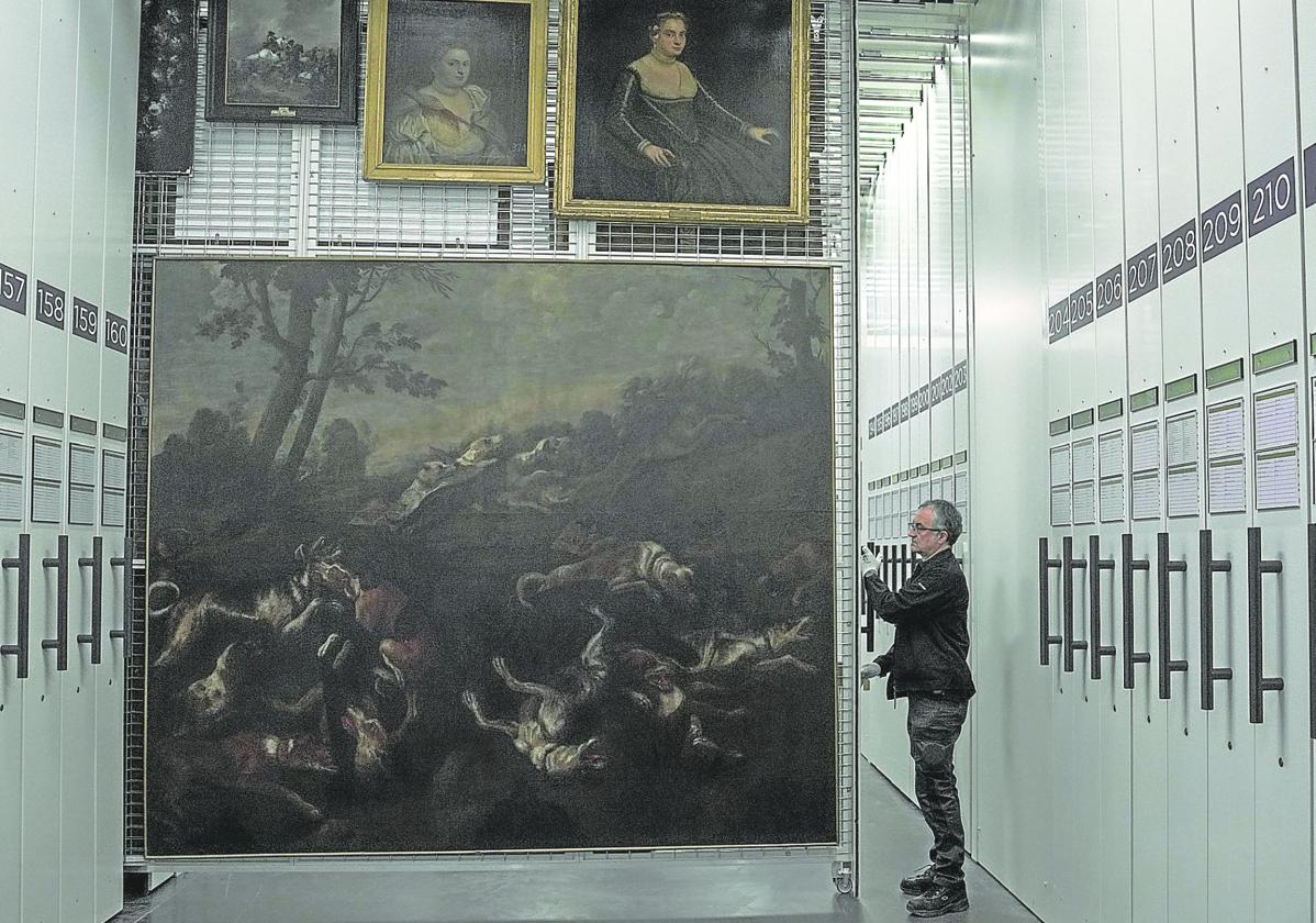 Mario Núñez, técnico de 'La brigada', descorre uno de los peines con cuadros de distintos formatos que se conservan en los almacenes del Museo del Prado.