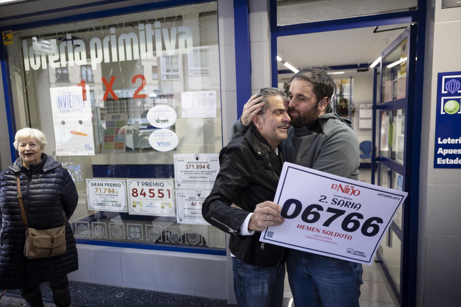 El responsable de la administración, Mikel Garmendia, celebra con su hijo Mikel el segundo premio de la lotería del Niño,