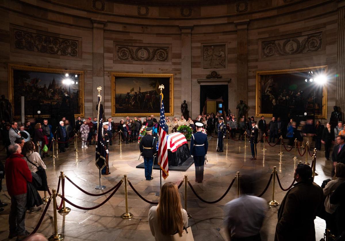 El público observa el ataúd cubierto con la bandera del expresidente Jimmy Carter en la Rotonda del Capitolio.