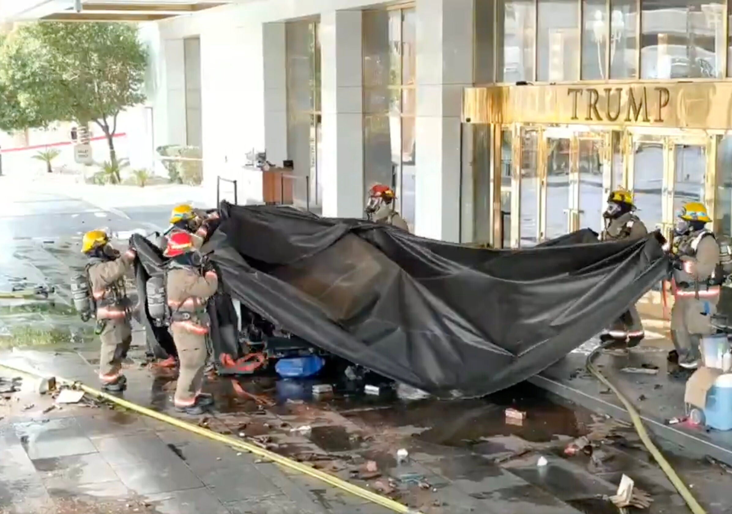 Bomberos retiran una lona después de apagar un Tesla Cybertruck que explotó frente al Hotel Trump en Las Vegas.