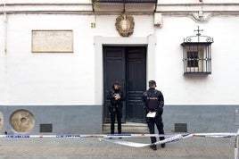 Dos policías junto a la puerta de la vivienda de Sevilla donde fallecieron este domingo los dos ancianos catedráticos.