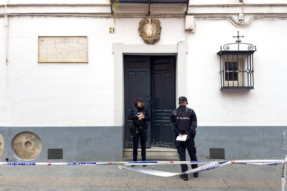 Dos policías junto a la puerta de la vivienda de Sevilla donde fallecieron este domingo los dos ancianos catedráticos.