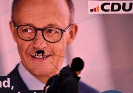 Un hombre pasa junto a un cartel de Friedrich Merz, candidato a canciller de la CDU, en Frankfurt