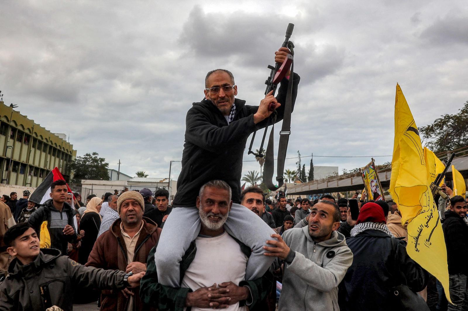 Uno de los presos palestinos liberados empuña un arma mientras es llevado a hombros por sus compatriotas.