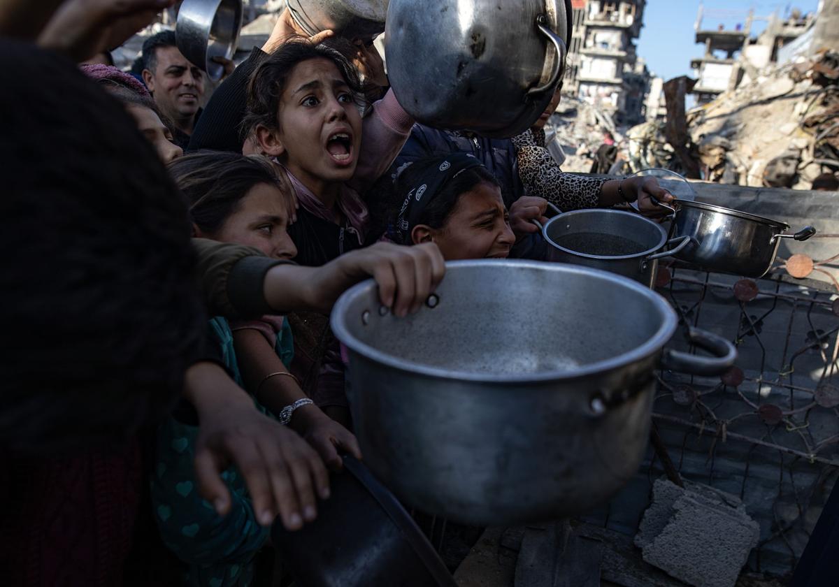 Niños palestinos se empujan para recibir una porción de comida de una cocina benéfica en Beit Lahia, en el norte de la Franja de Gaza.