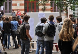 Un grupo de adolescentes consulta unos listados en el patio de su instituto.