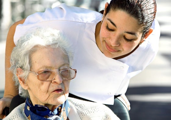 Una cuidadora atiende a una anciana en su domicilio.