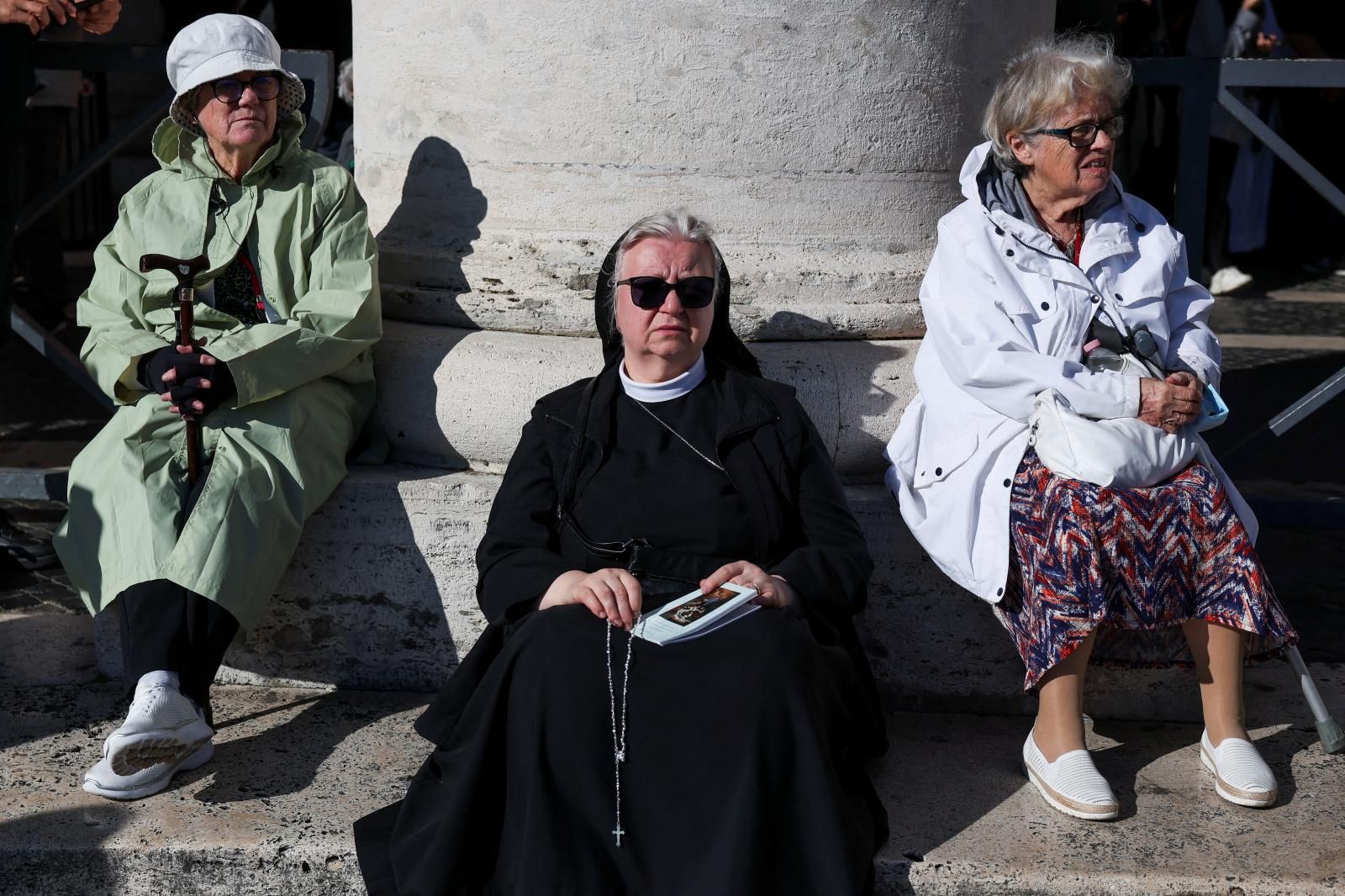 Una monja sostiene un rosario mientras la gente se reúne antes de la misa.