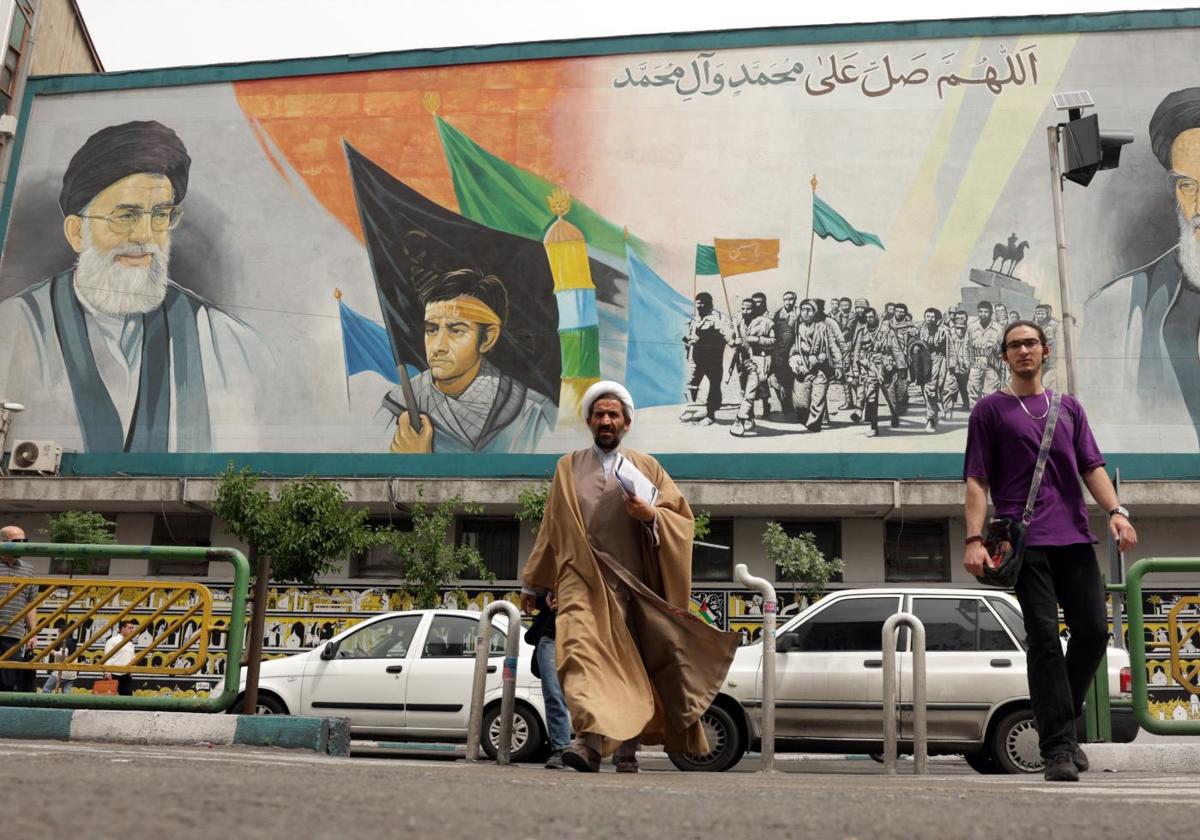 Un clérigo iraní camina junto a un enorme mural del Líder Supremo, el ayatolá Alí Jamenei, en una calle de Teherán.
