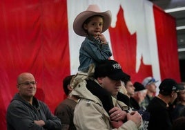 Una niña participa en un acto de campaña en Canadá subido a los hombros de su padre.