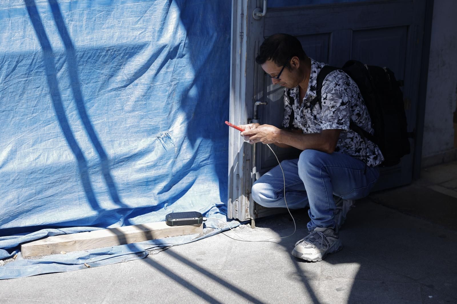 Un joven carga su teléfono gracias a una batería solar
